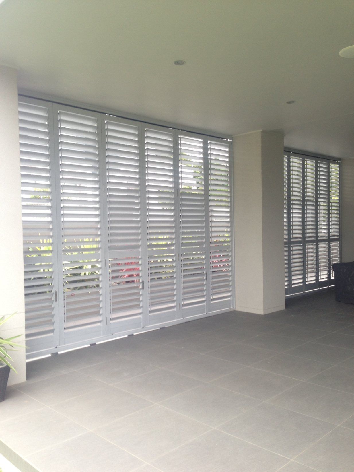 A Patio with A Table and Chairs and Shutters on The Windows — Lifestyle Aluminium Fabrication In Albion Park Rail, NSW
