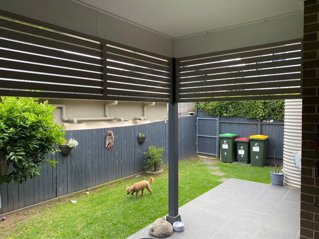 A Dog is Walking on a Patio Next to a Fence — Lifestyle Aluminium Fabrication In Kiama, NSW