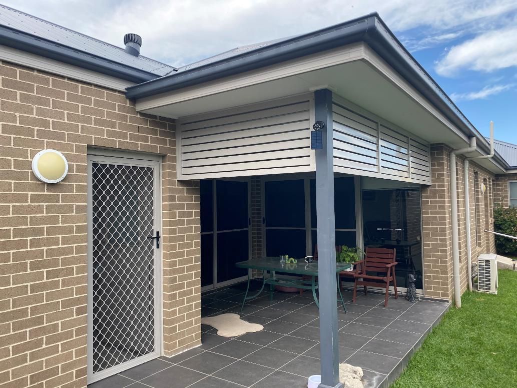A Brick House With a Patio and a Table and Chairs on It  — Lifestyle Aluminium Fabrication In Shellharbour, NSW