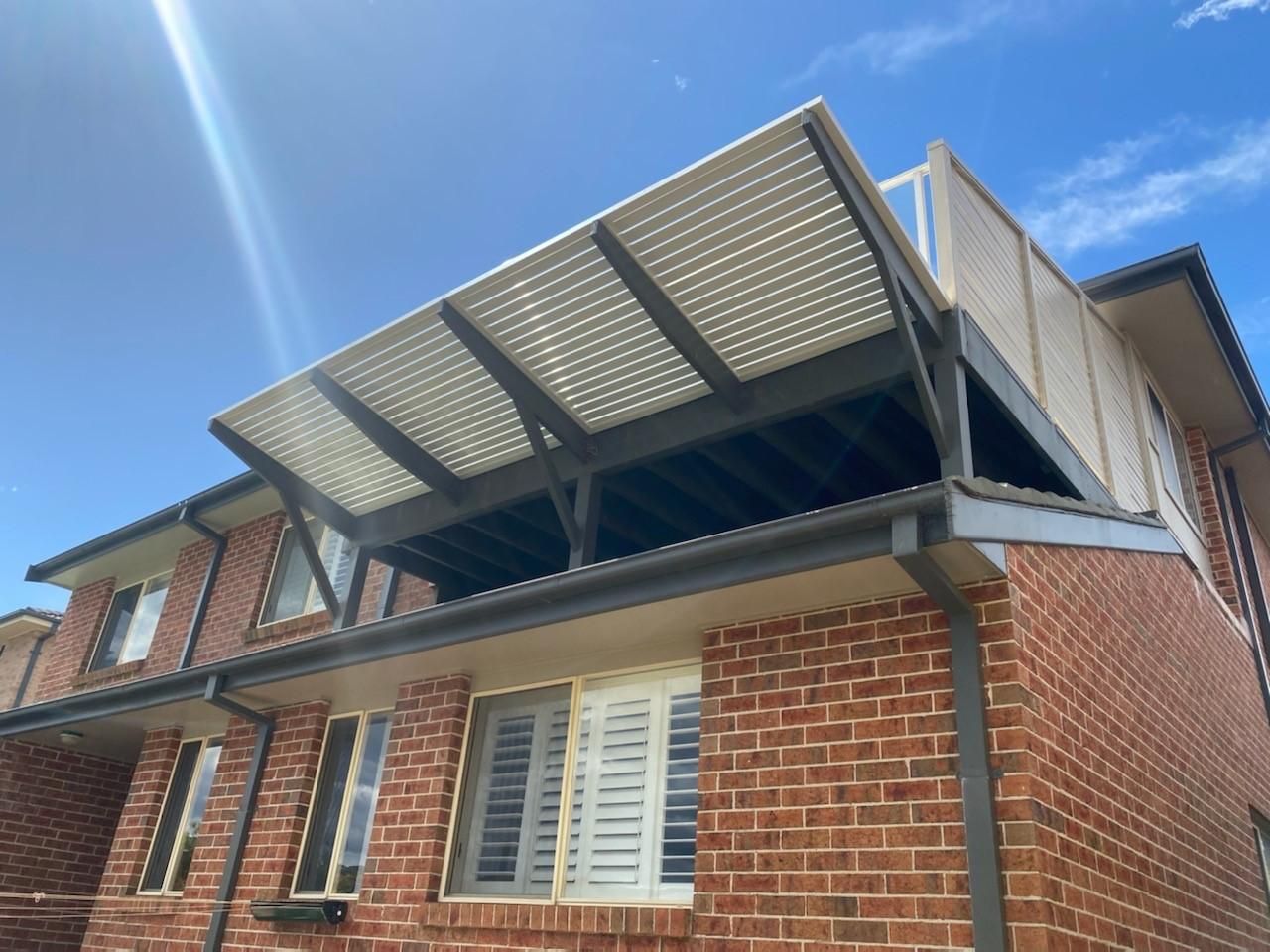 A Brick House With a Balcony on the Top of It — Lifestyle Aluminium Fabrication In Wollongong, NSW