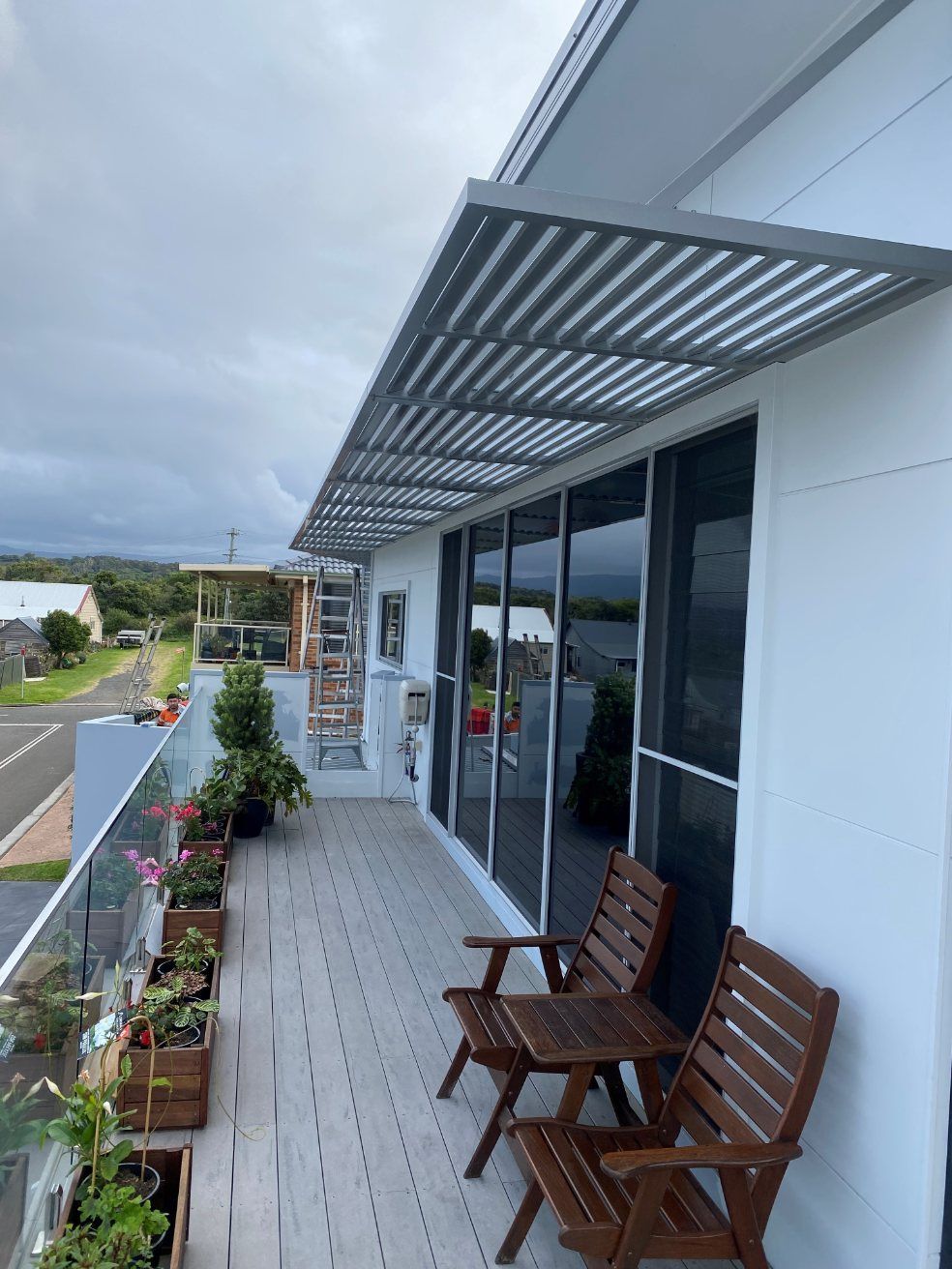A Balcony with Two Wooden Chairs and A Table — Lifestyle Aluminium Fabrication In Albion Park Rail, NSW