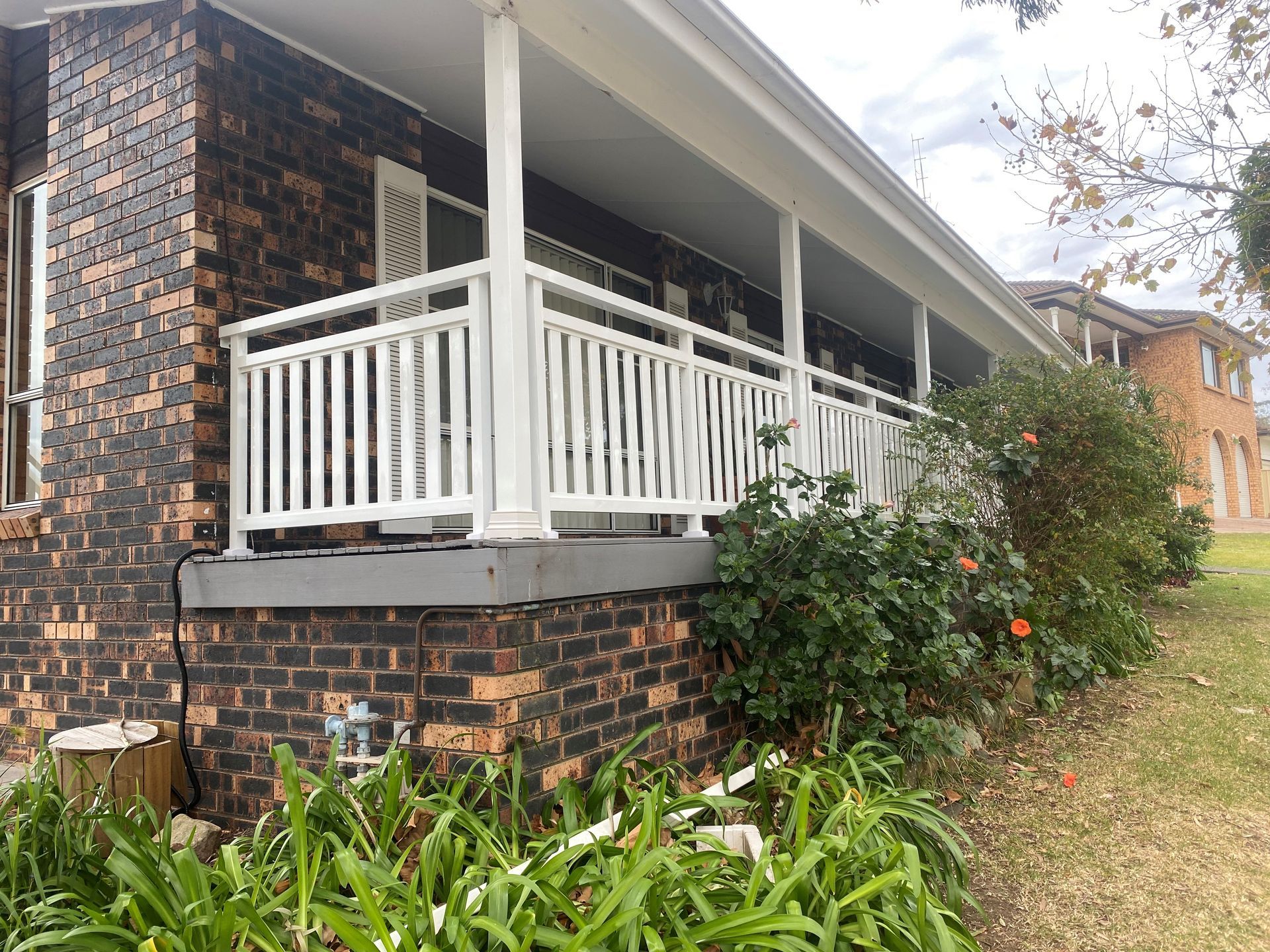 A brick house with a white railing on the porch.