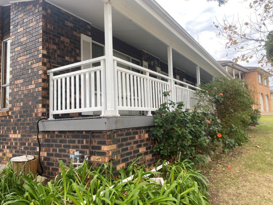 A Brick House with A White Porch and A White Railing — Lifestyle Aluminium Fabrication In Albion Park Rail, NSW