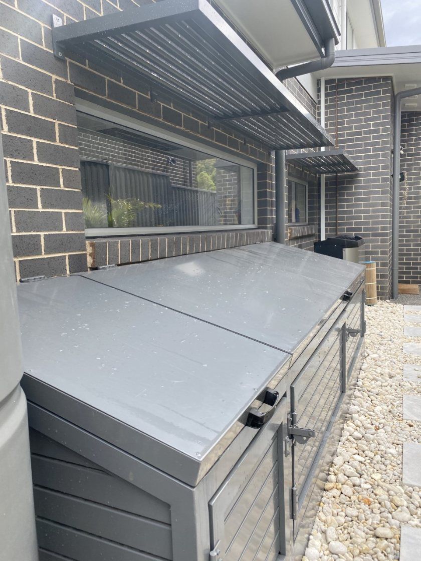 A White Fence Is Surrounding a Brick Building — Lifestyle Aluminium Fabrication In Albion Park Rail, NSW