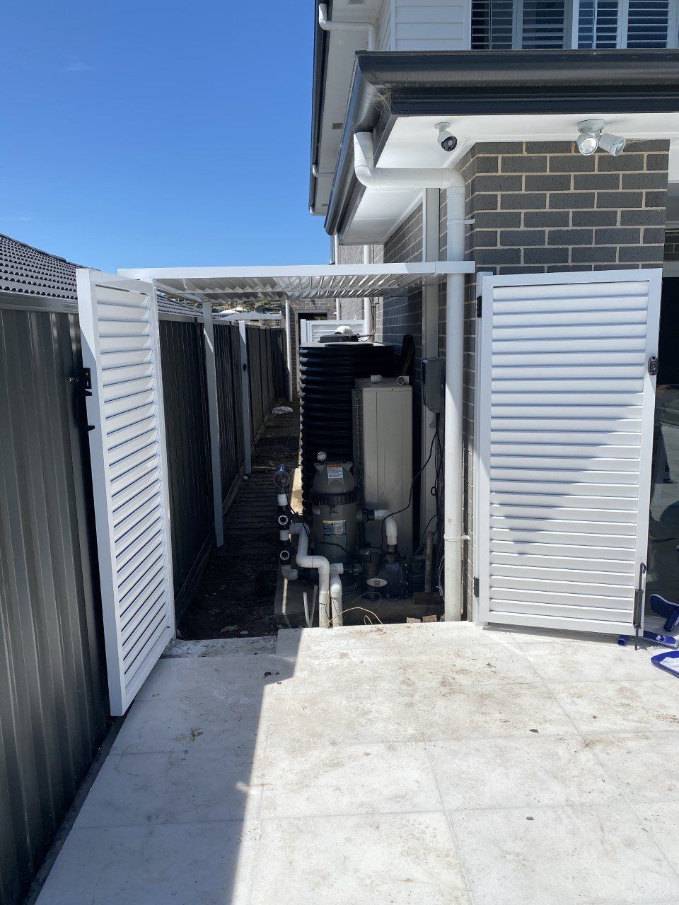 A White Fence Is Surrounding a Brick Building — Lifestyle Aluminium Fabrication In Albion Park Rail, NSW