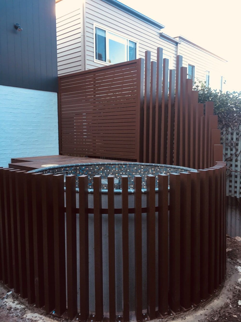 A Trampoline Is Behind A Wooden Fence In A Backyard — Lifestyle Aluminium Fabrication In Albion Park Rail, NSW