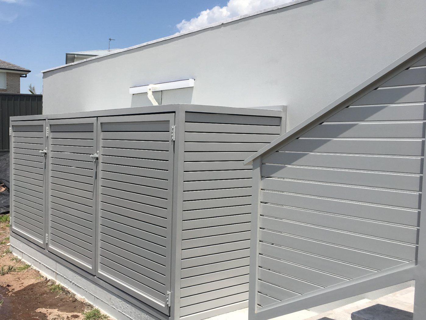 A White Fence Is Surrounding a Brick Building — Lifestyle Aluminium Fabrication In Albion Park Rail, NSW
