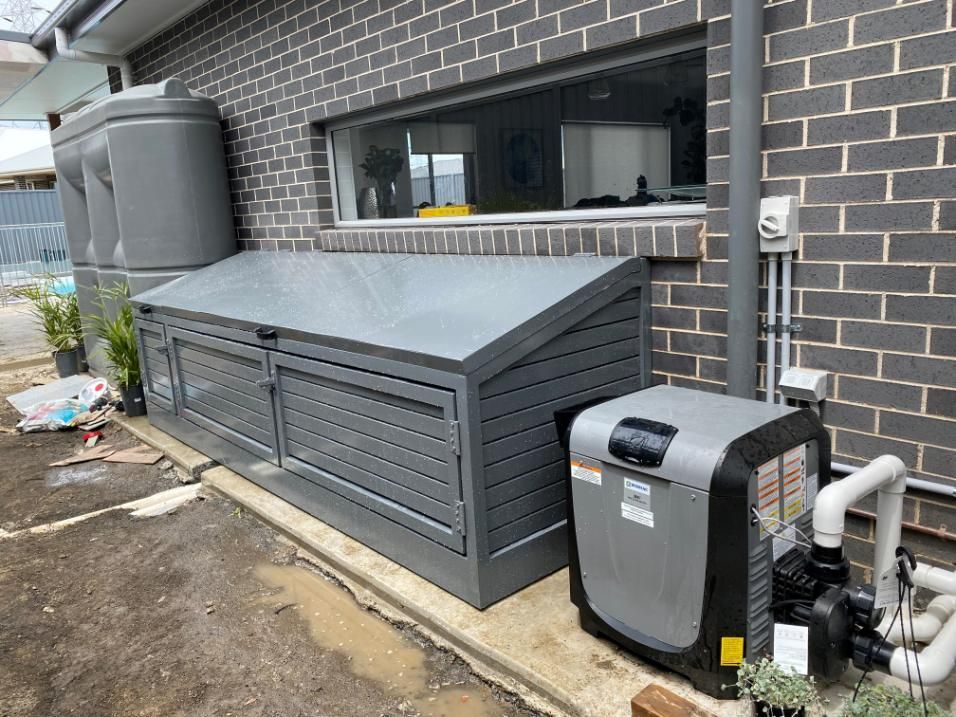 A Swimming Pool Heater is Sitting Next to a Brick Building — Lifestyle Aluminium Fabrication In Wollongong, NSW