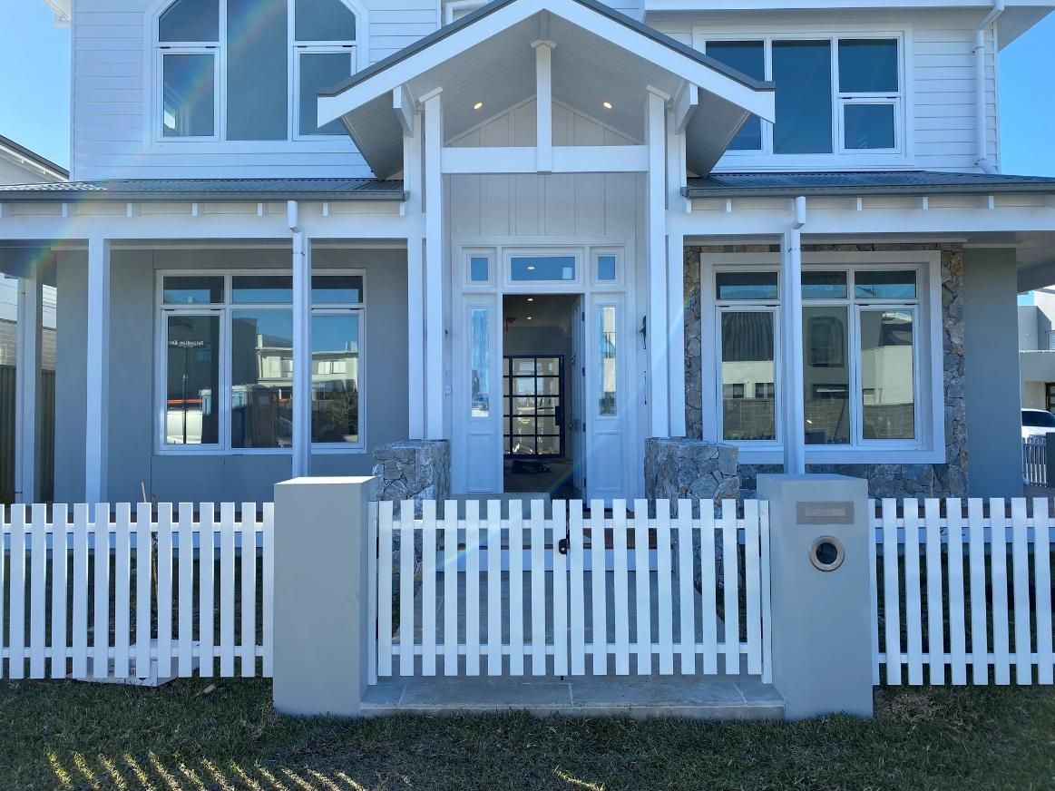 A Large White House With a White Picket Fence in Front of It — Lifestyle Aluminium Fabrication In Fairy Meadow, NSW