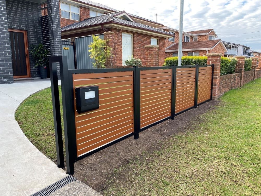 A Wooden Fence With A Mailbox In Front Of A House  — Lifestyle Aluminium Fabrication In Albion Park Rail, NSW