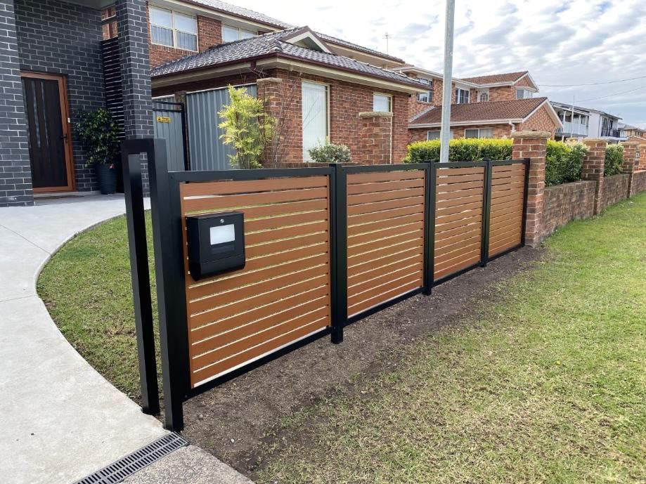 A Wooden Fence With a Mailbox in Front of a House  — Lifestyle Aluminium Fabrication In Kiama, NSW