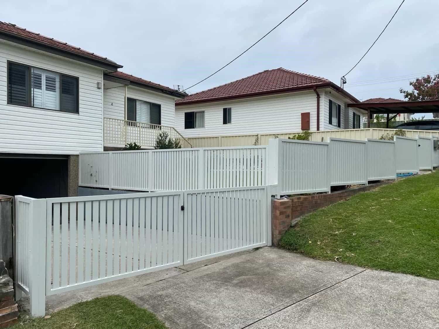 A White Fence Surrounds a Driveway in Front of A House — Lifestyle Aluminium Fabrication In Dapto, NSW