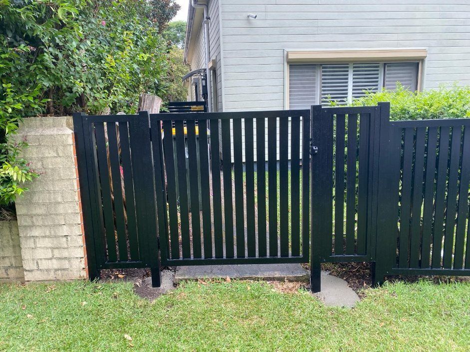 A Black Fence with A Gate in Front of A House — Lifestyle Aluminium Fabrication In Albion Park Rail, NSW