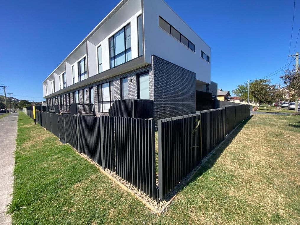 A Large White Building With a Black Fence Around It — Lifestyle Aluminium Fabrication In Kiama, NSW