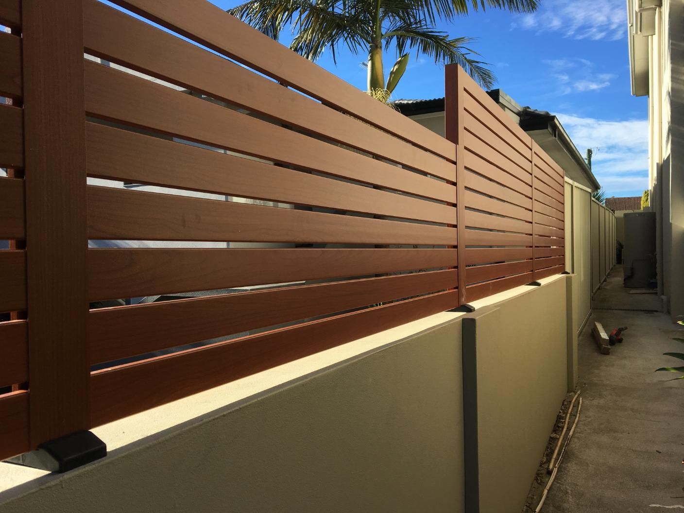 A Wooden Fence is Along the Side of a Building — Lifestyle Aluminium Fabrication In Fairy Meadow, NSW