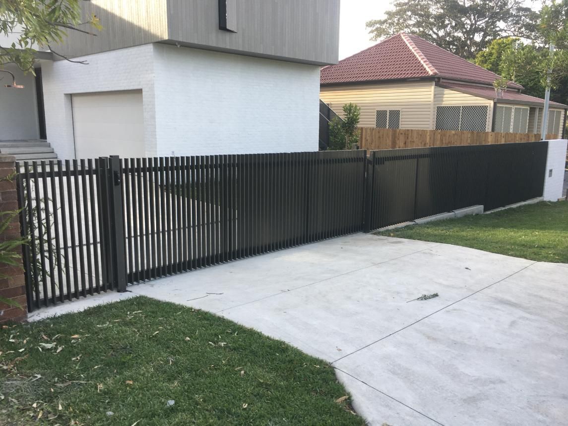 A Black Fence is Surrounding a Driveway in Front of a House — Lifestyle Aluminium Fabrication In Kiama, NSW