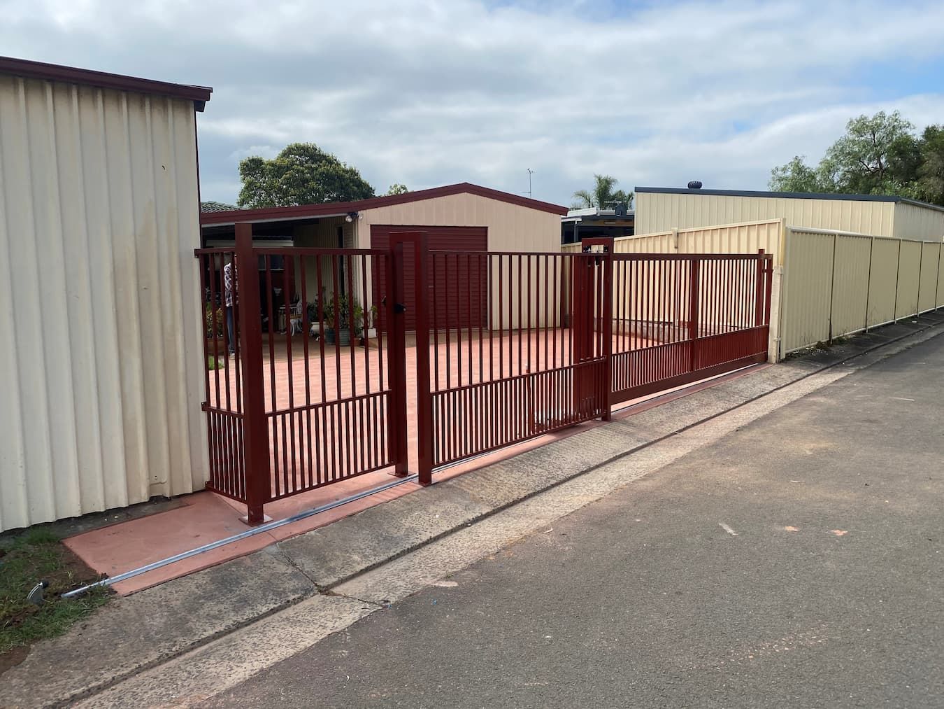 A Red Fence Is Surrounding a Garage and A House — Lifestyle Aluminium Fabrication In Kiama, NSW
