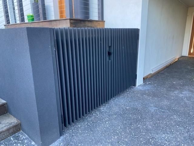 A Black Gate is Sitting on the Side of a Building — Lifestyle Aluminium Fabrication In Dapto, NSW