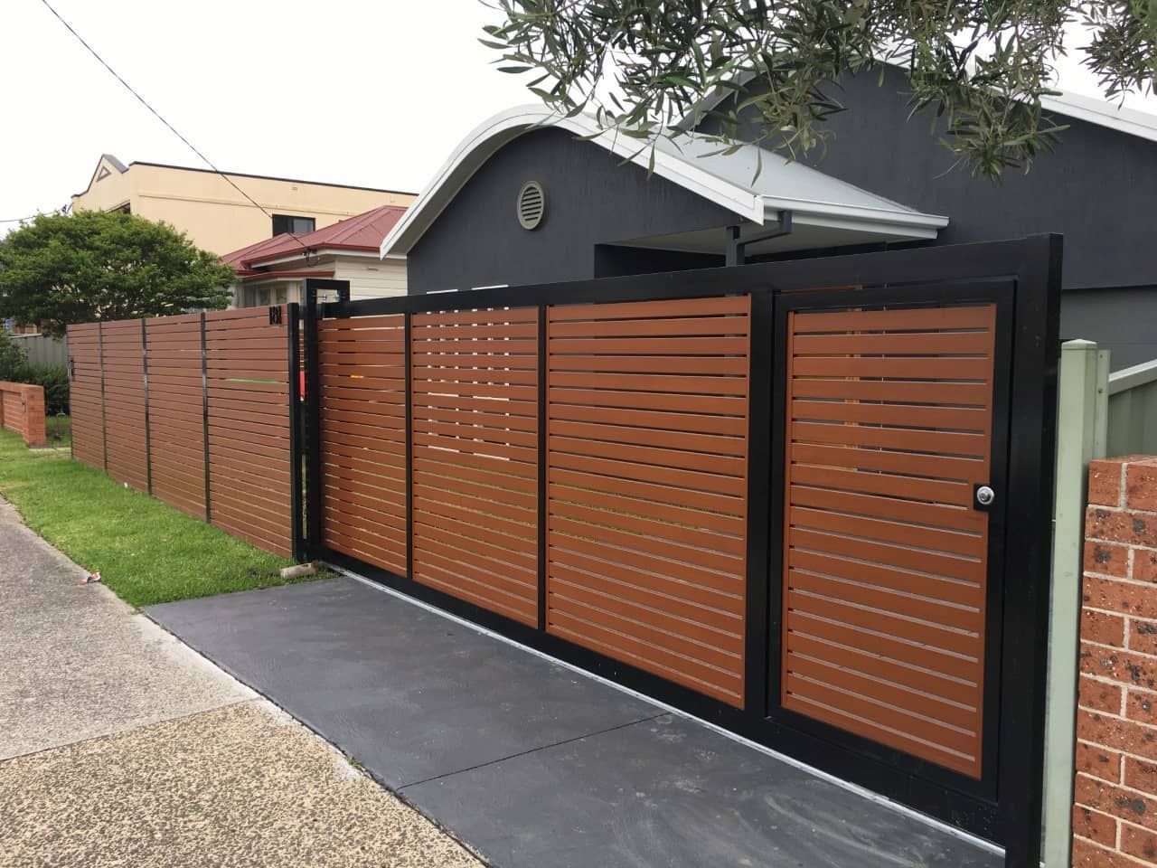 A Sliding Gate with A Wooden Fence in Front of A House — Lifestyle Aluminium Fabrication In Shellharbour, NSW