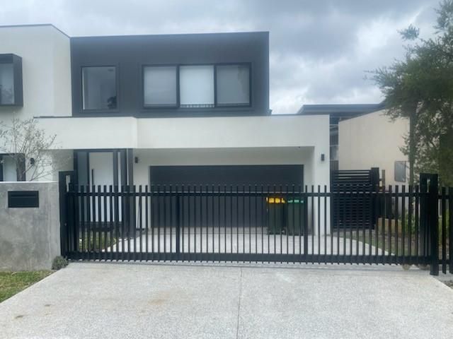 A White House With a Black Fence in Front of It — Lifestyle Aluminium Fabrication In Fairy Meadow, NSW