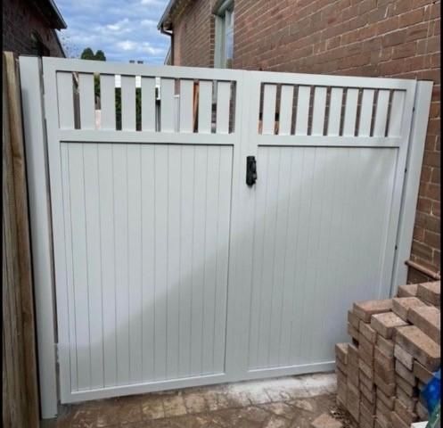 A White Gate is Sitting in Front of a Brick Building With Bricks in Front — Lifestyle Aluminium Fabrication In Fairy Meadow, NSW