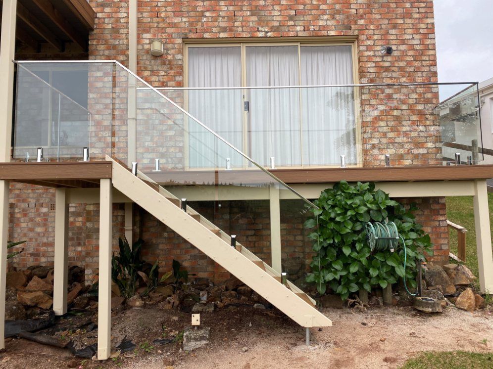 A Brick House with A Deck and Stairs with A Glass Railing — Lifestyle Aluminium Fabrication In Albion Park Rail, NSW