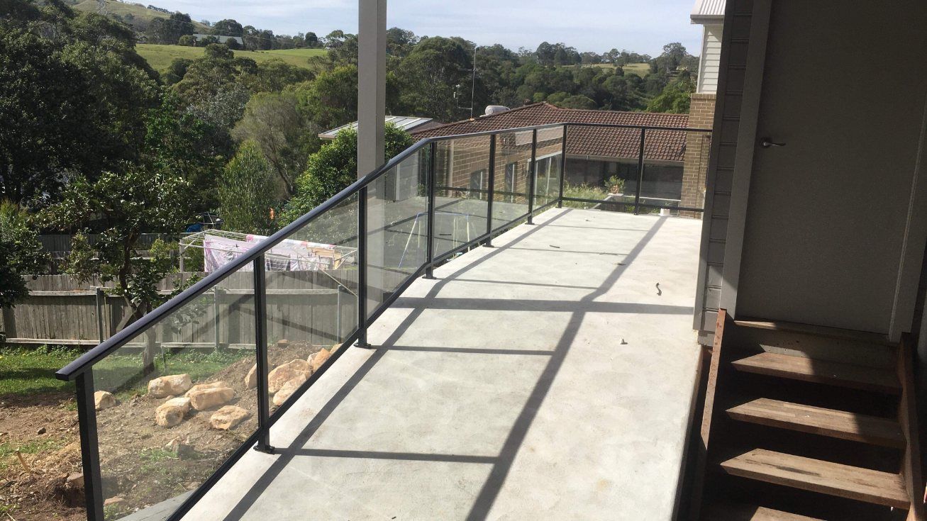 A Balcony with A Glass Railing and Stairs Leading up To It — Lifestyle Aluminium Fabrication In Albion Park Rail, NSW