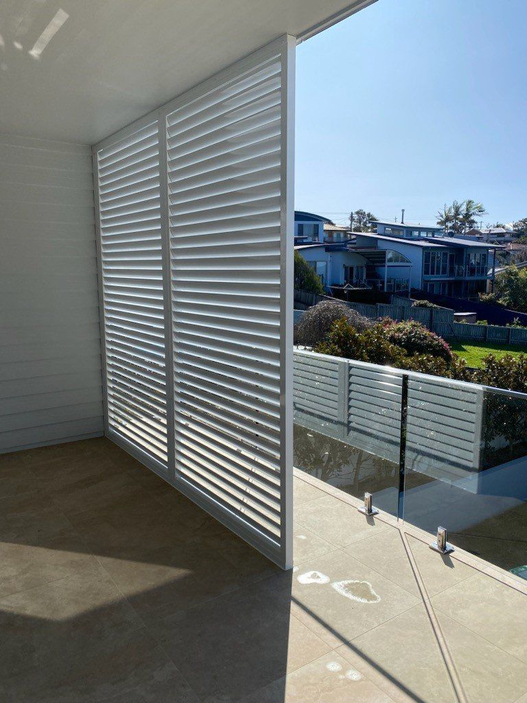 A Balcony with White Shutters and A Glass Railing — Lifestyle Aluminium Fabrication In Albion Park Rail, NSW