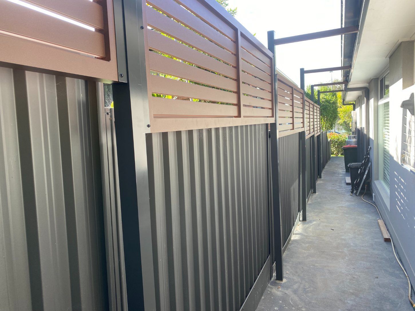 A Fence Along a Sidewalk Next to A House — Lifestyle Aluminium Fabrication In Albion Park Rail, NSW