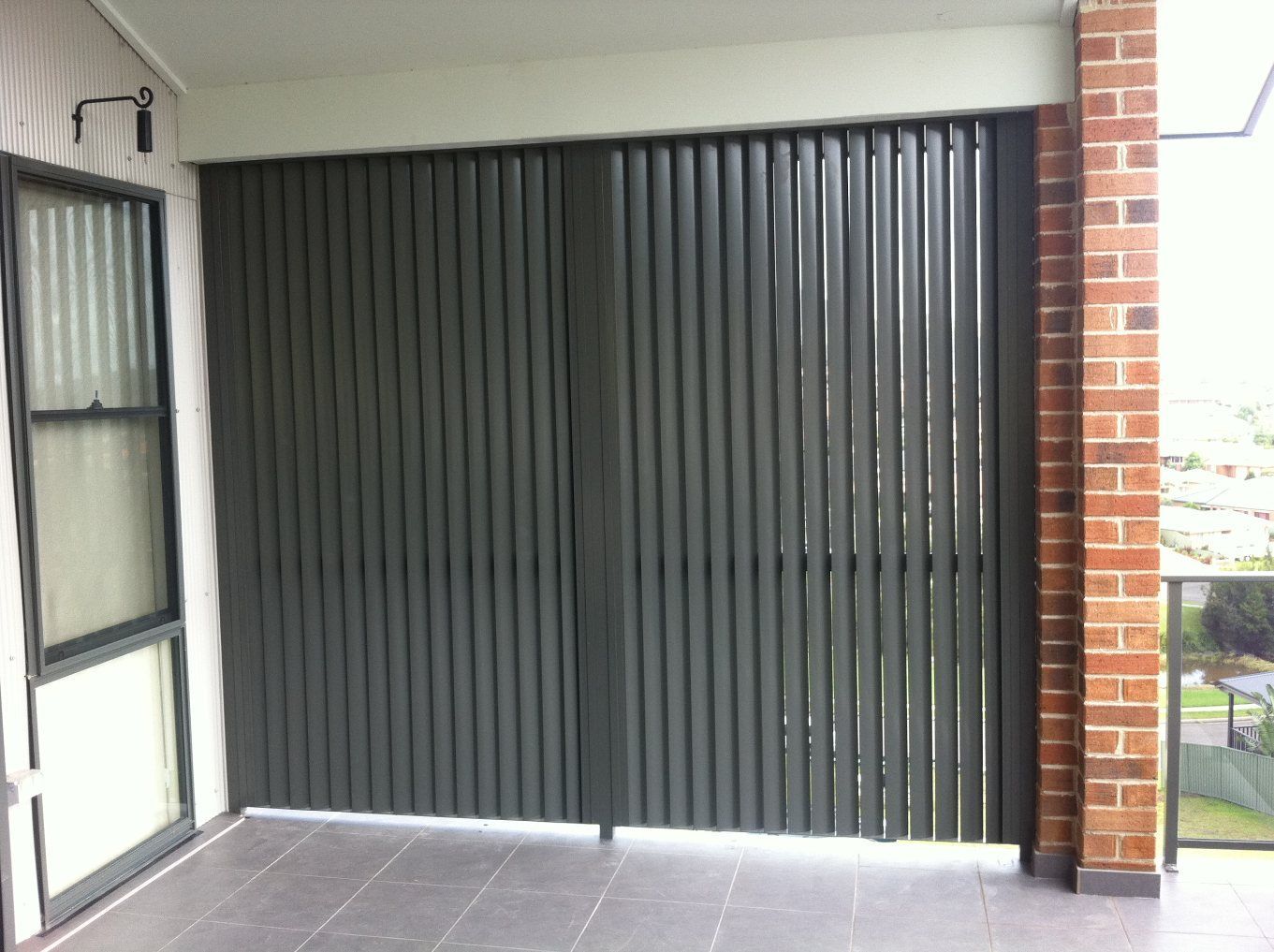 A Balcony with A Brick Wall and Blinds on It — Lifestyle Aluminium Fabrication In Albion Park Rail, NSW