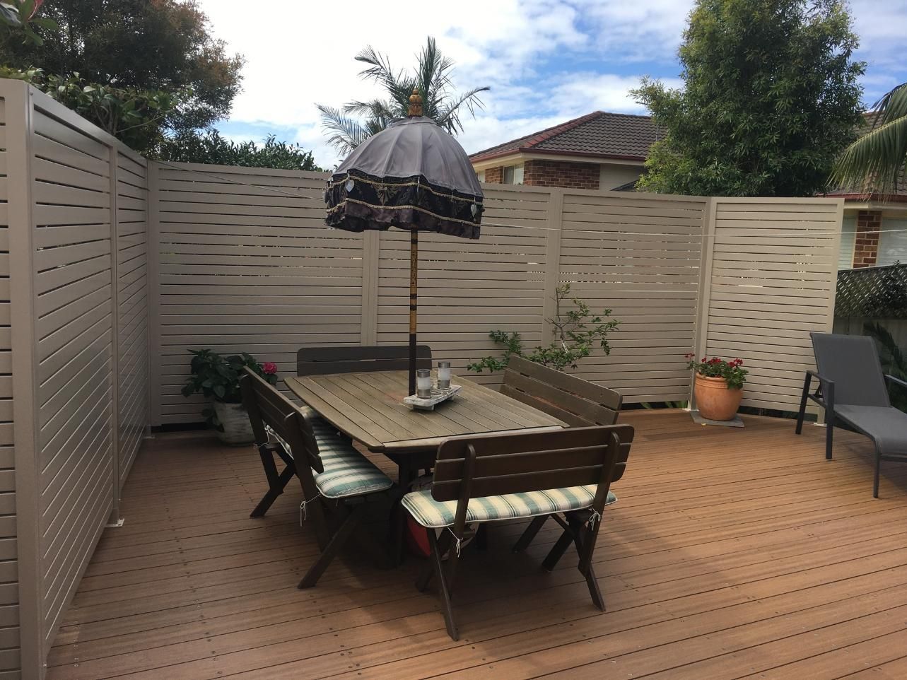 A Patio With A Table And Chairs And An Umbrella — Lifestyle Aluminium Fabrication In Albion Park Rail, NSW