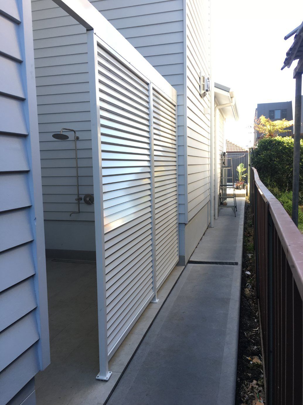 A Walkway Between Two Buildings with Shutters on The Side — Lifestyle Aluminium Fabrication In Albion Park Rail, NSW
