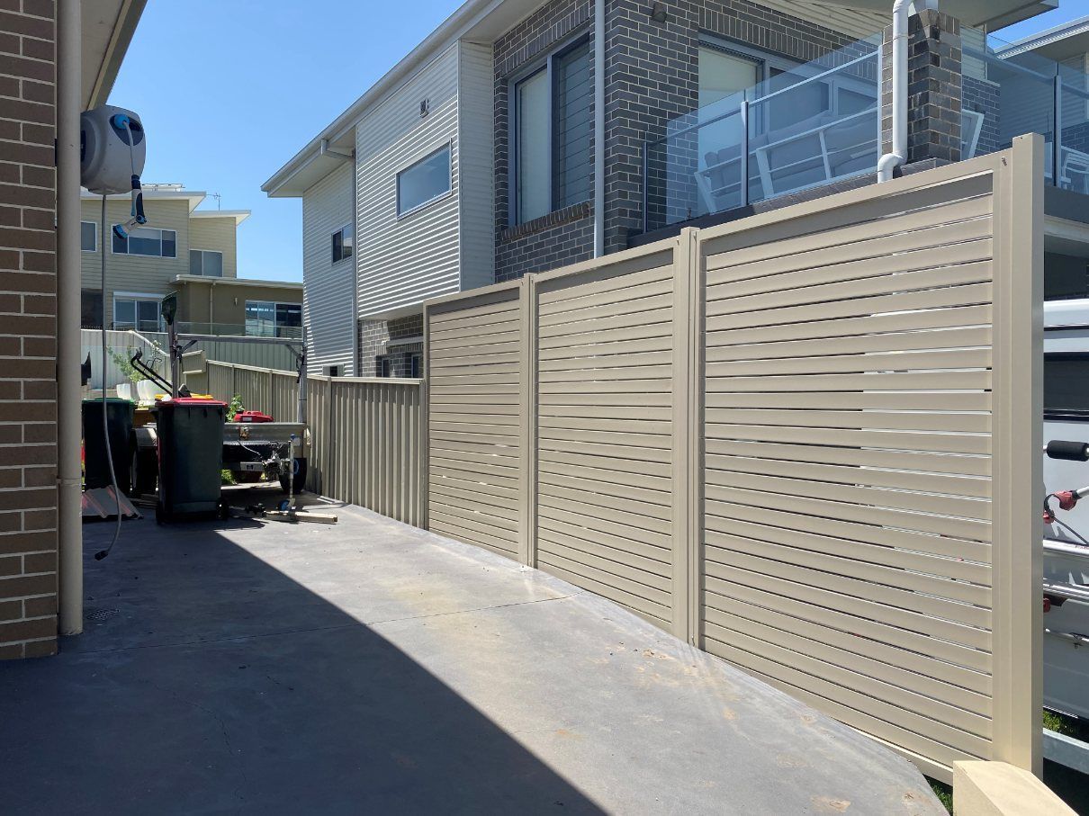 A Fence Is Surrounding a Driveway in Front of A House — Lifestyle Aluminium Fabrication In Albion Park Rail, NSW