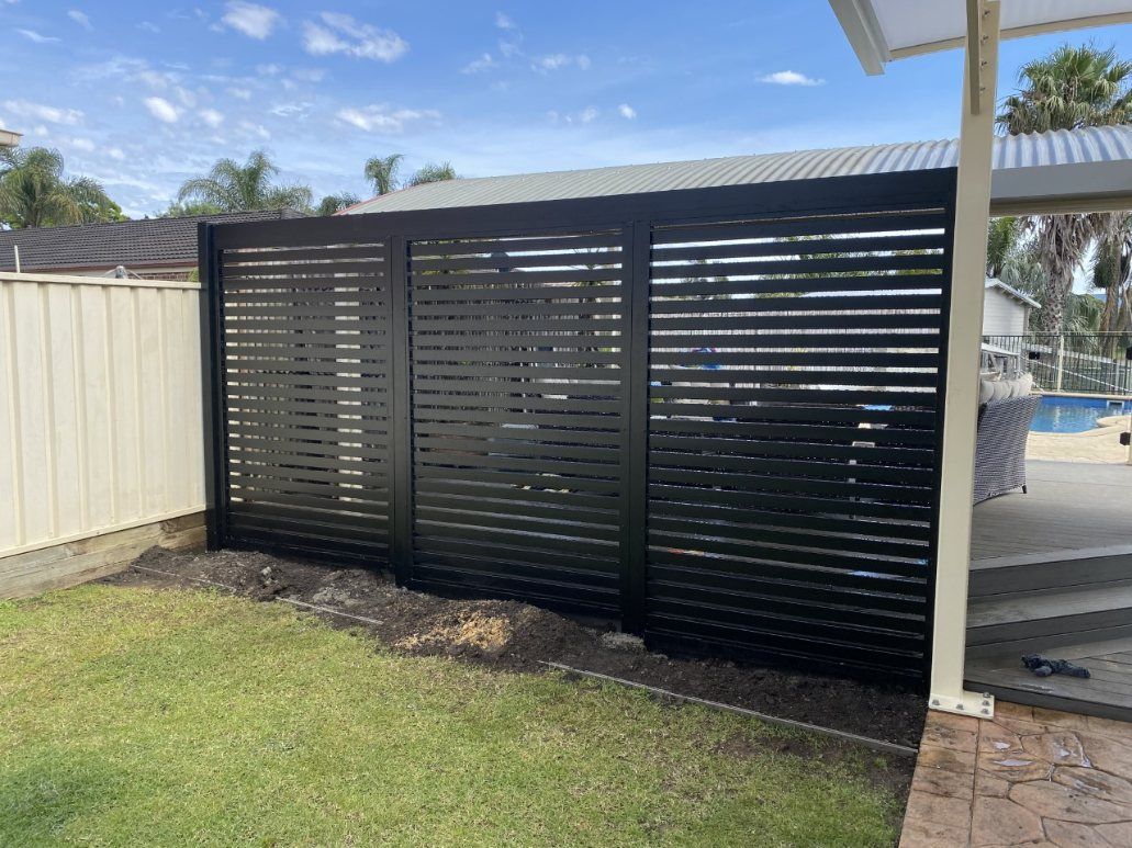 A Black Fence Is in The Backyard of A House — Lifestyle Aluminium Fabrication In Albion Park Rail, NSW