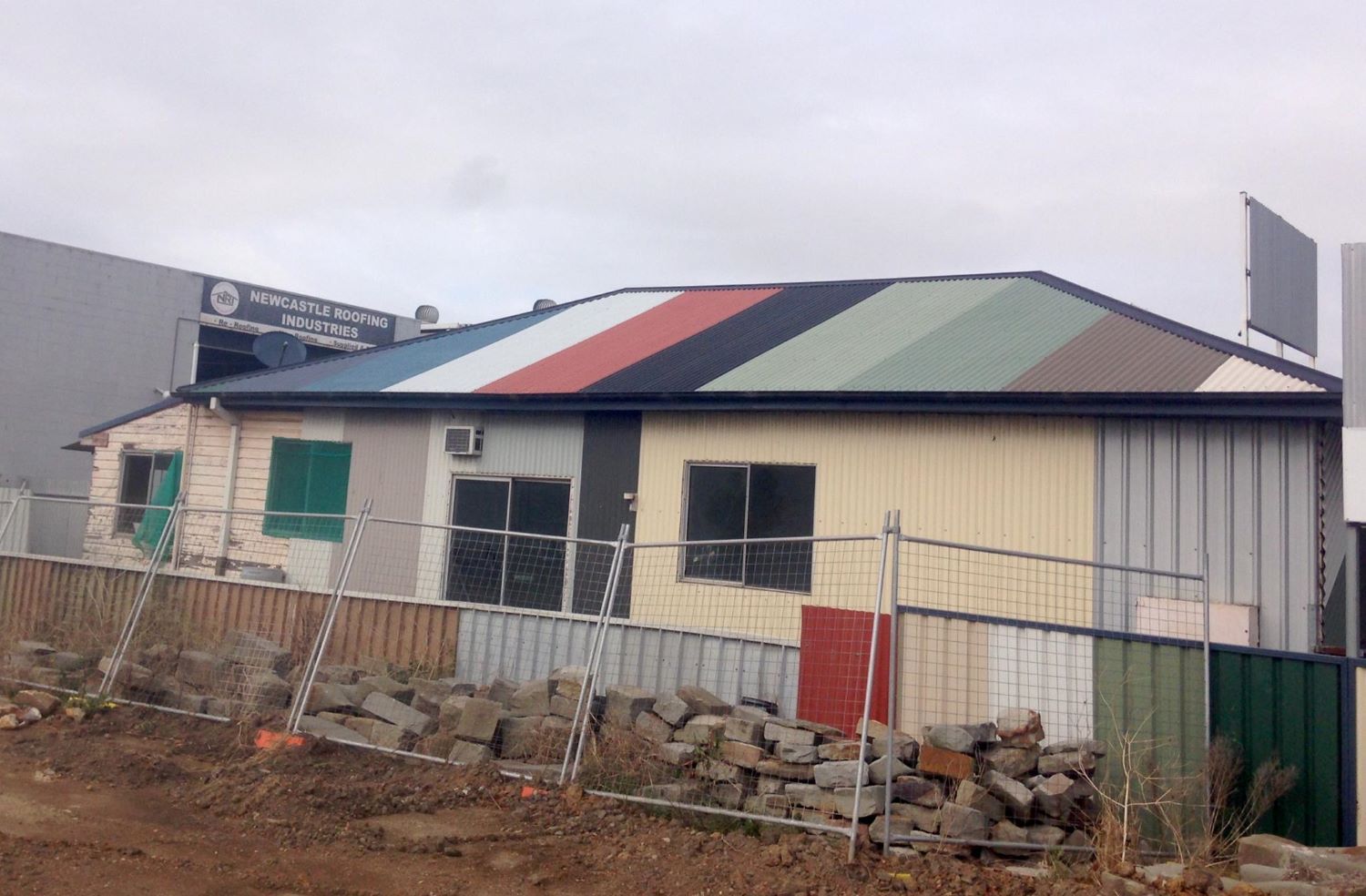 A House With A Colorful Roof And A Fence In Front Of It — In-Time Roofing In Newcastle, NSW