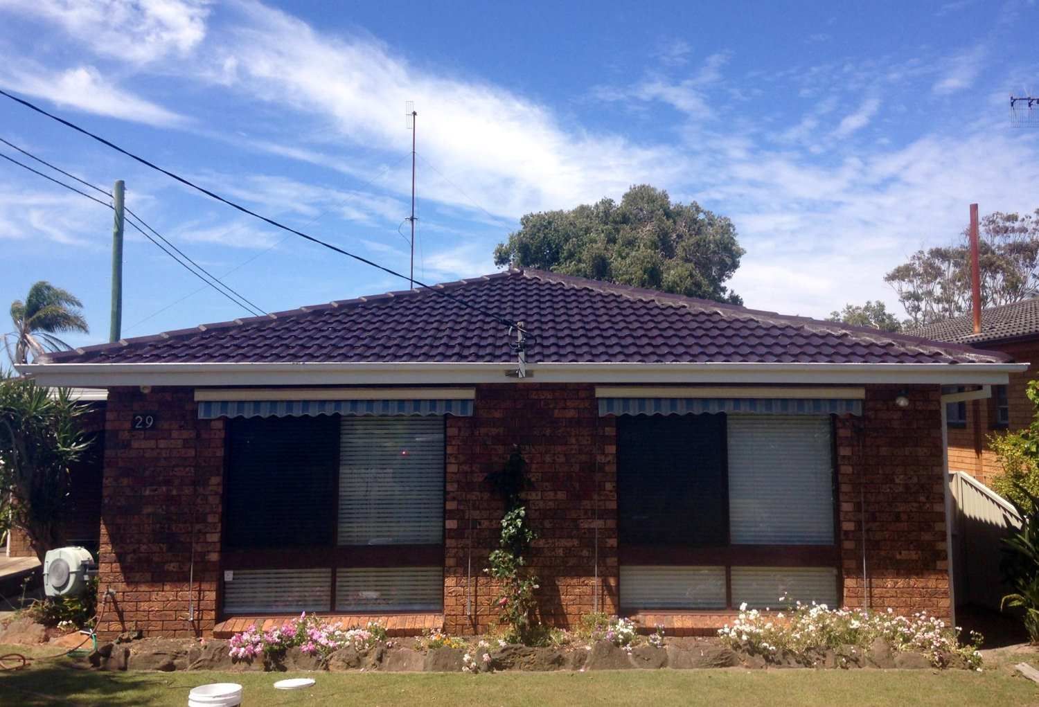 A Brick House With A Purple Roof And A Blue Sky In The Background — In-Time Roofing In Lake Macquarie, NSW