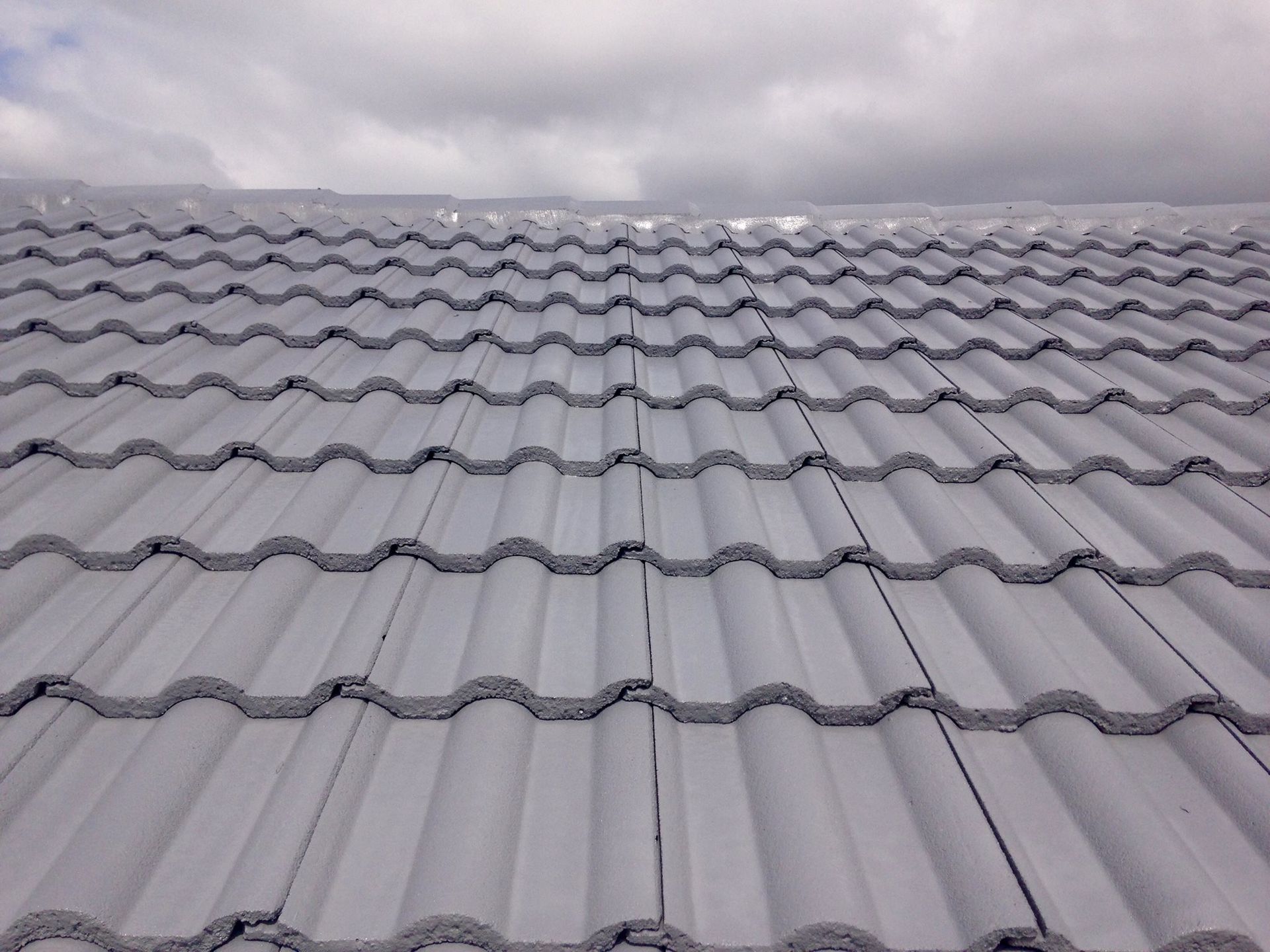 A White Tiled Roof With A Cloudy Sky In The Background — In-Time Roofing In Newcastle, NSW