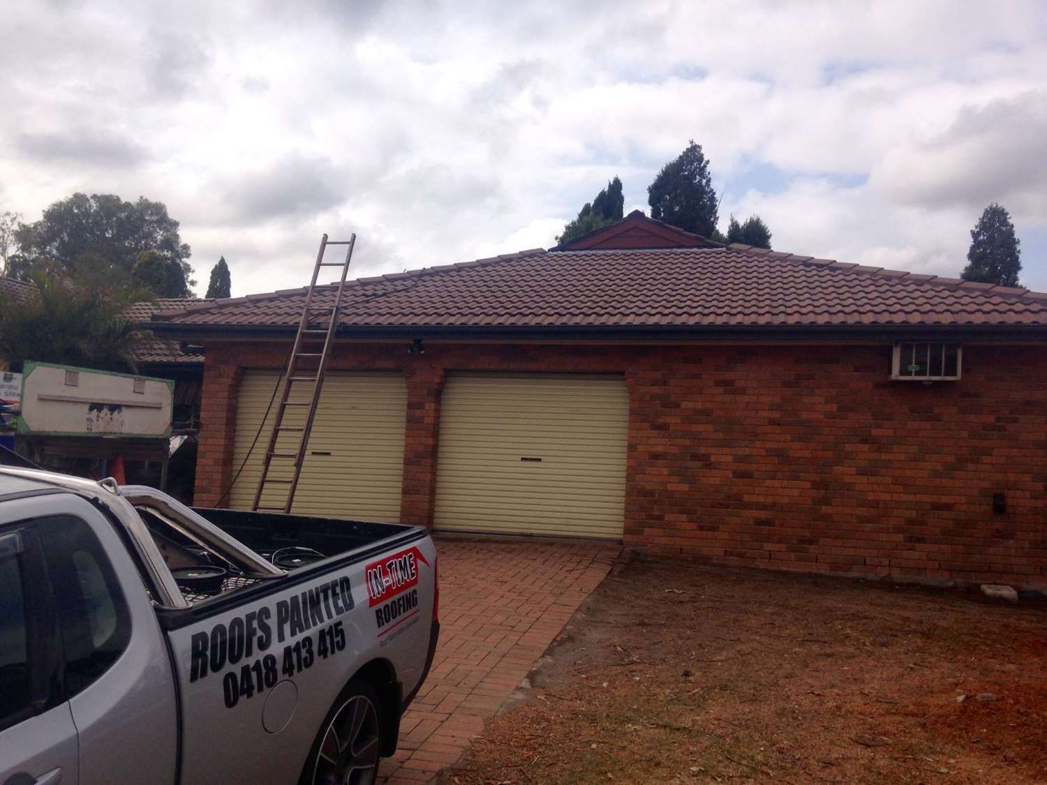 A Roofs Painter Truck Is Parked In Front Of A Brick House — In-Time Roofing In Newcastle, NSW