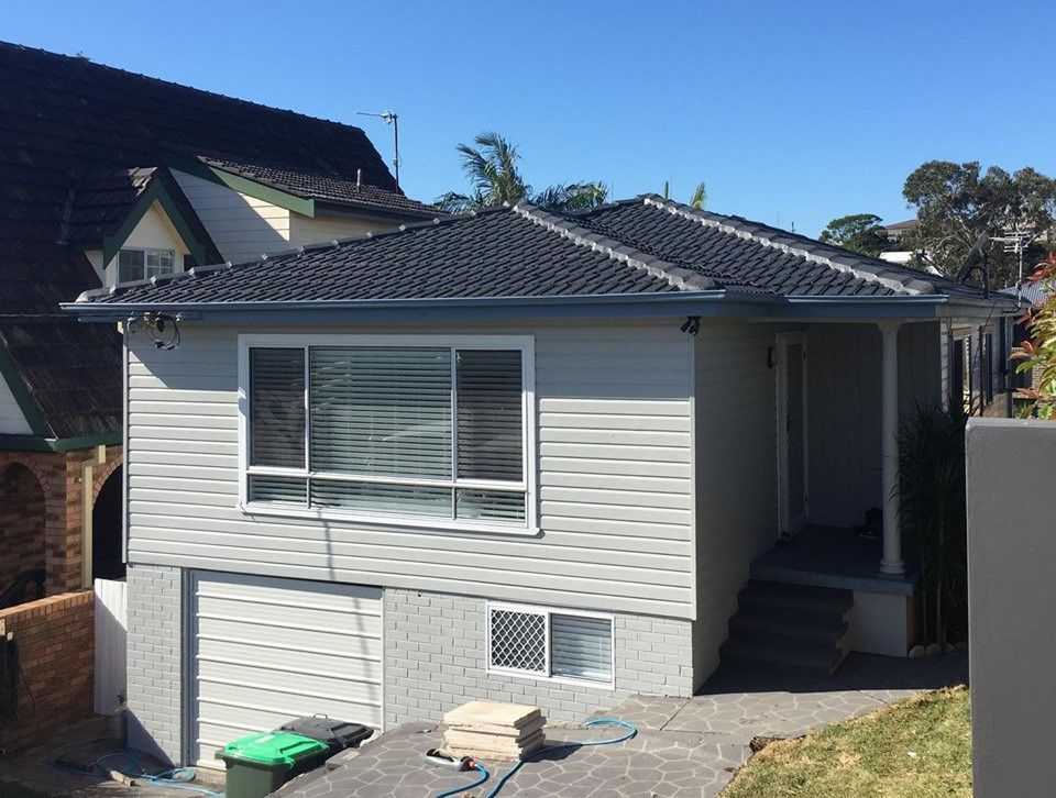 A Small White House With A Black Roof And A Garage — In-Time Roofing In Newcastle, NSW