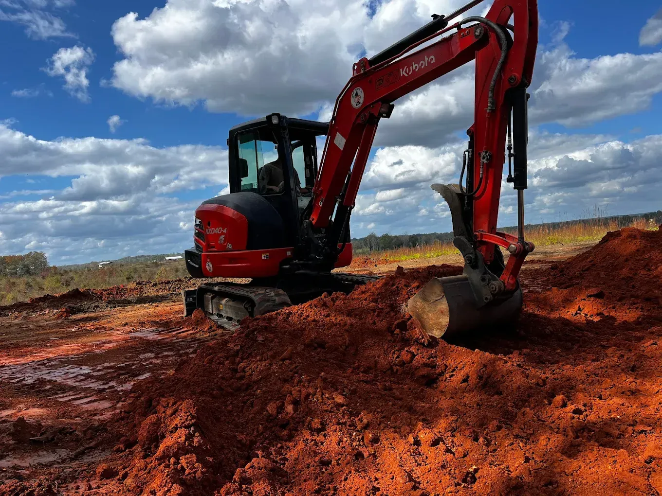 Woman in straw hat smiles, holding wine glass near a lake.
