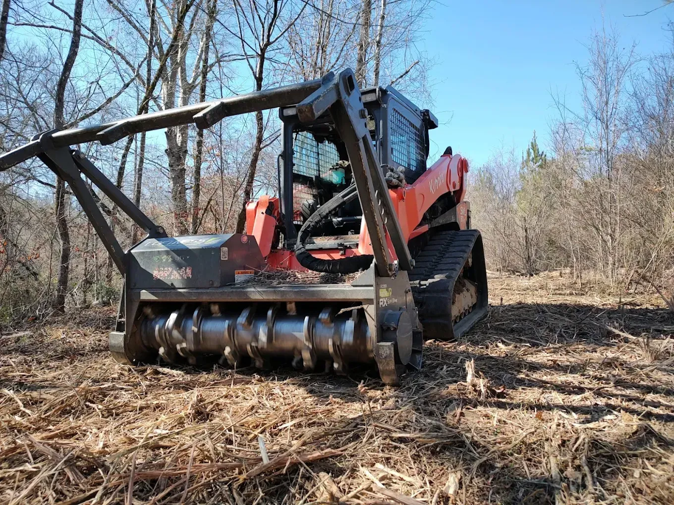 Woman in straw hat smiles, holding wine glass near a lake.