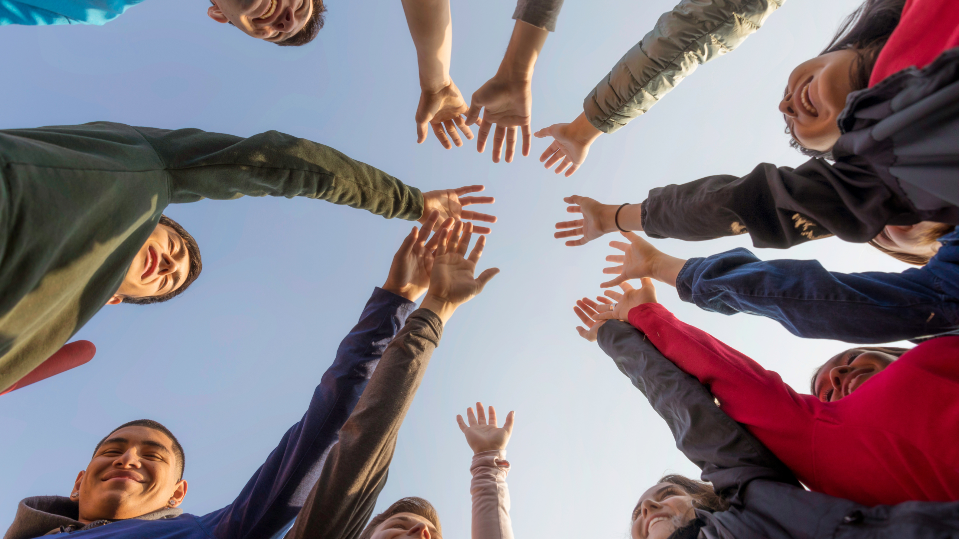 A group of people are standing in a circle with their hands in the air.