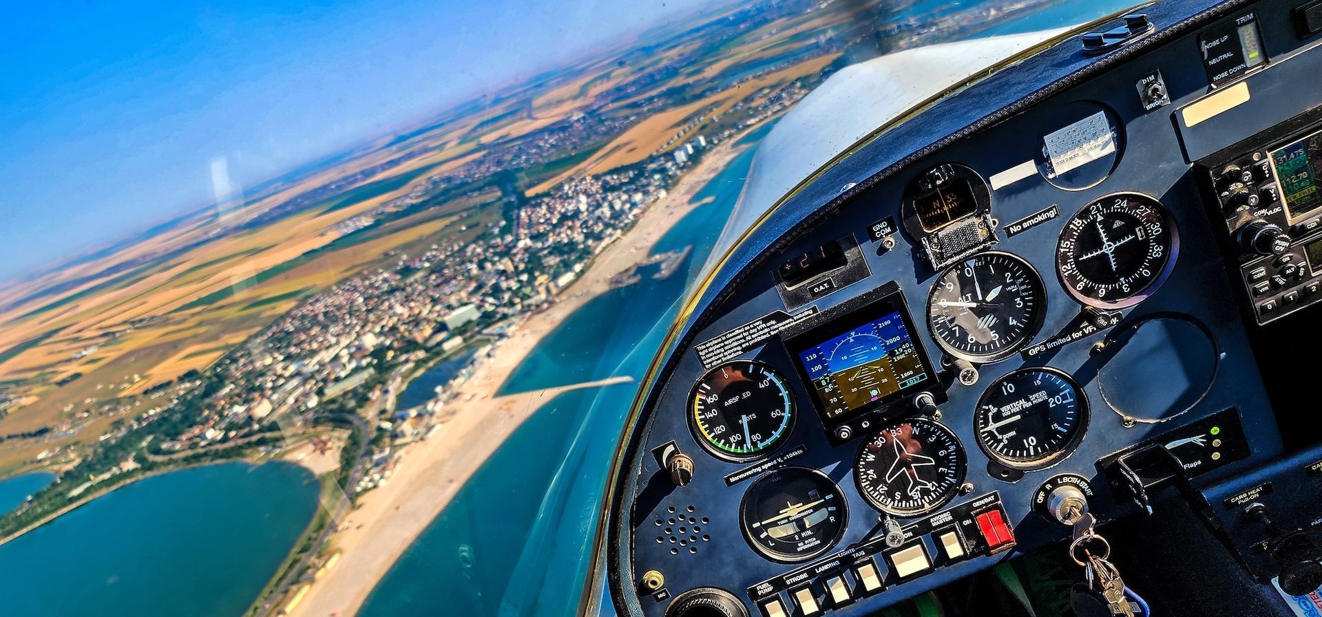 Cockpit view during private pilot license training flight showing aircraft instruments and scenic aerial landscape.