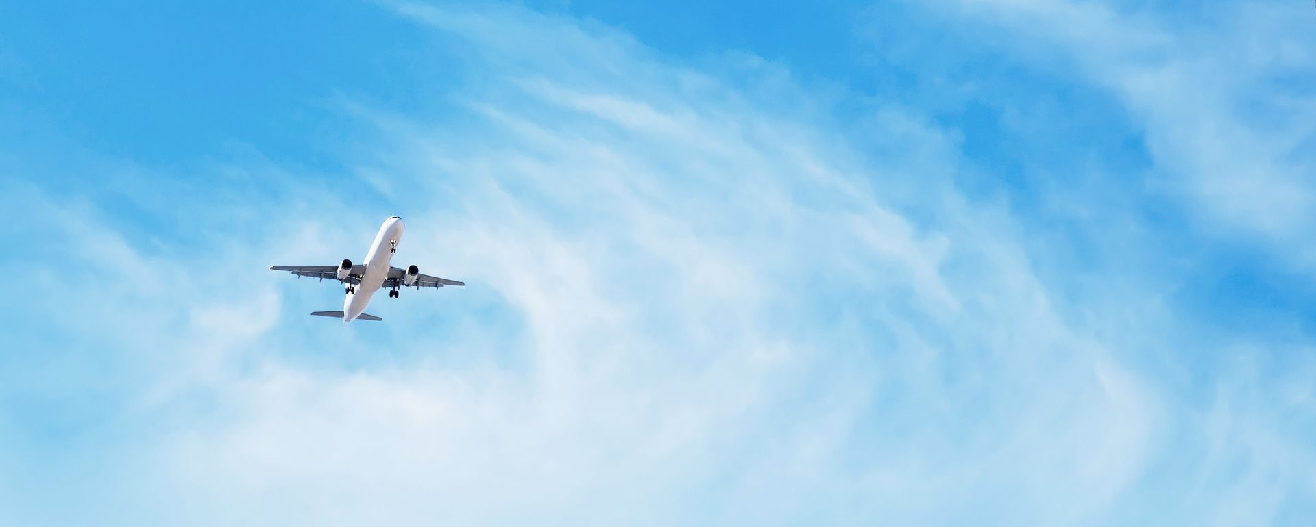 A commercial jet soaring through a bright blue sky, representing the career destination for students pursuing an aviation license.
