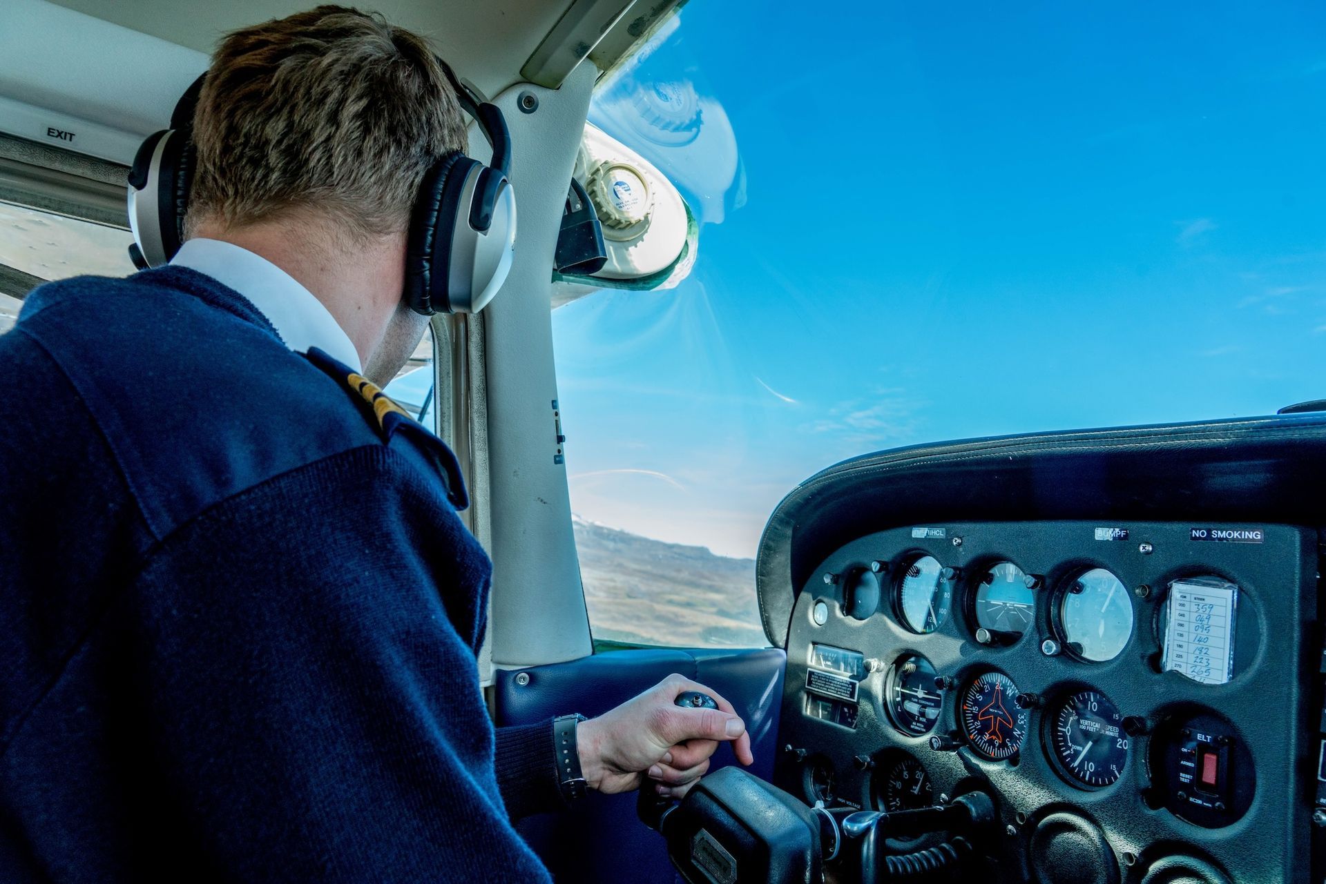 Student pilot flying with headset on and scanning cockpit gauges, practicing concepts essential for 