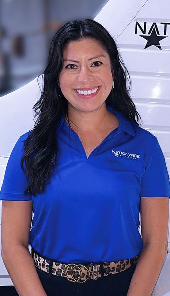 Smiling woman standing beside aircraft for team photo.
