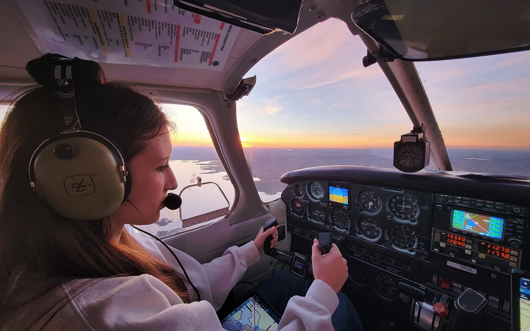 Student pilot and instructor flying at sunset inside cockpit.