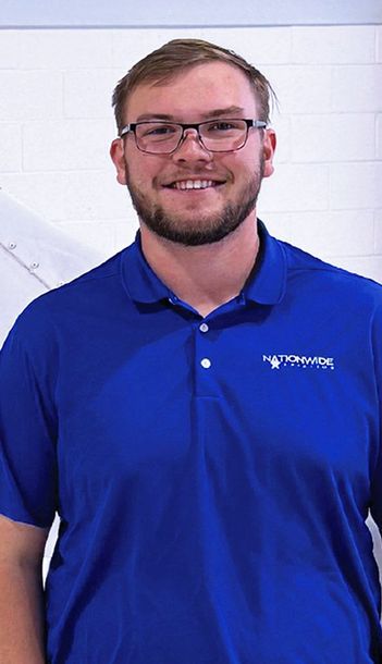 Smiling man standing indoors for aviation team portrait.