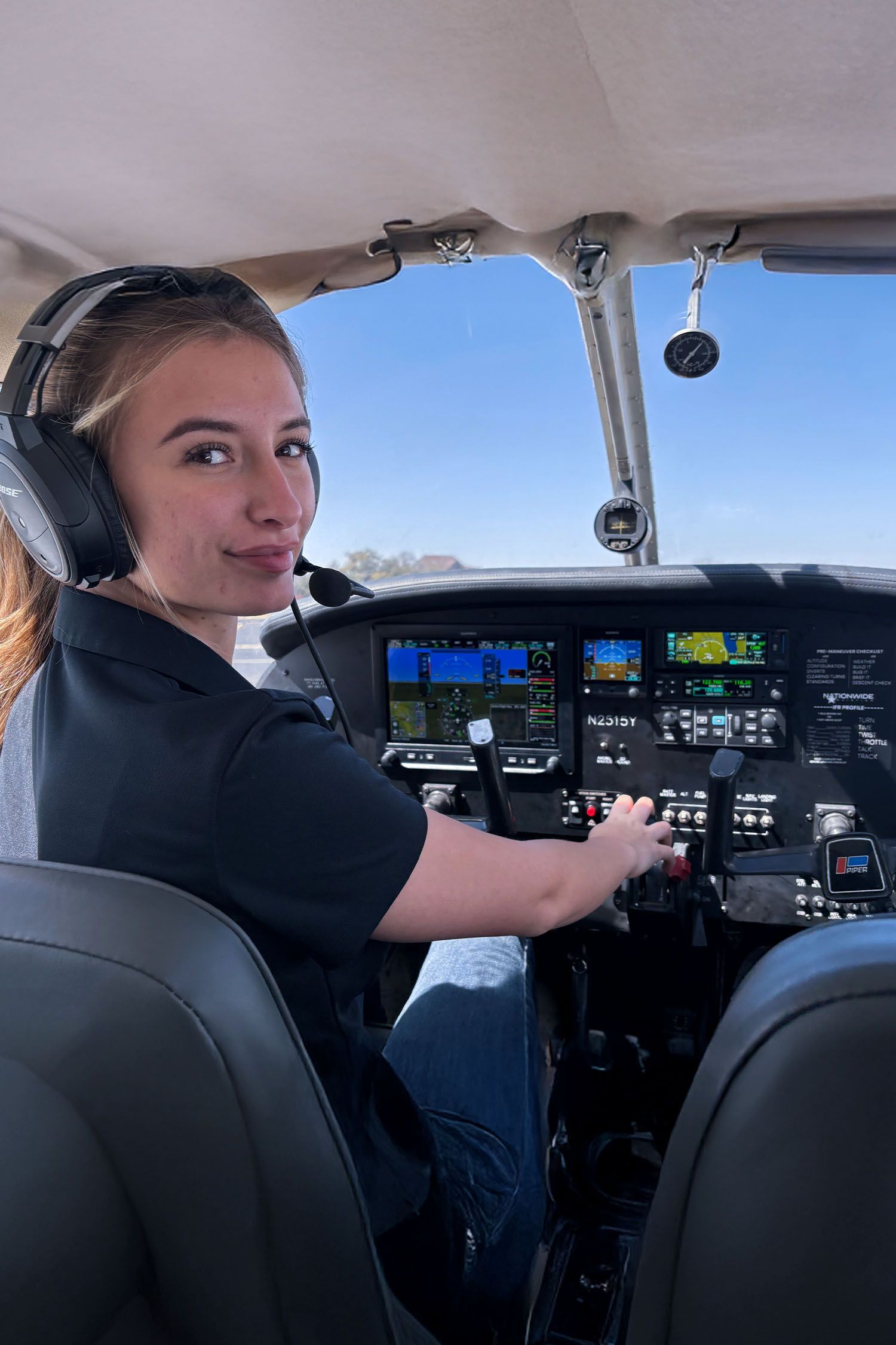 Student sitting inside cockpit wearing a headset during training flight.