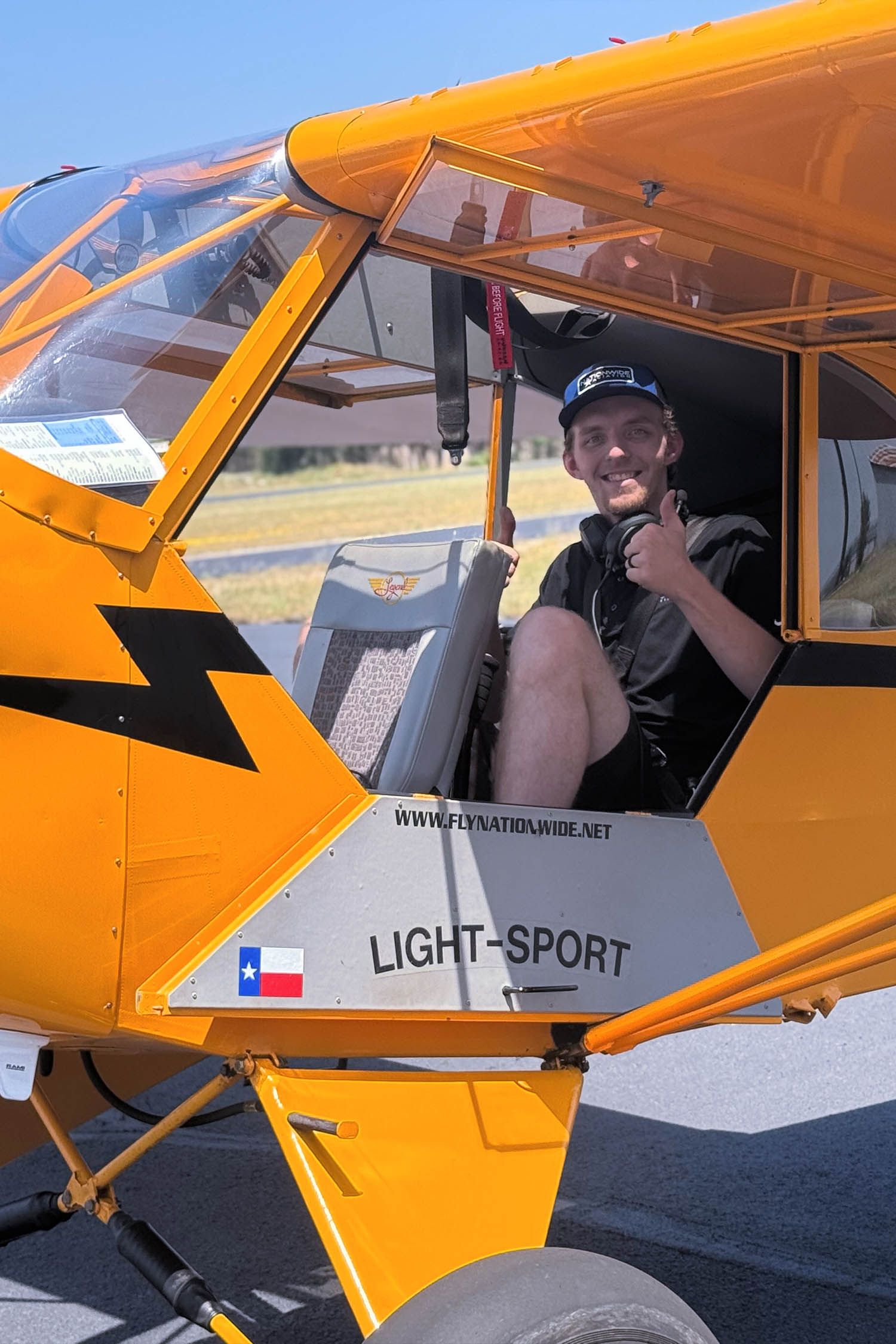 Student sitting inside a yellow taildragger aircraft during training.